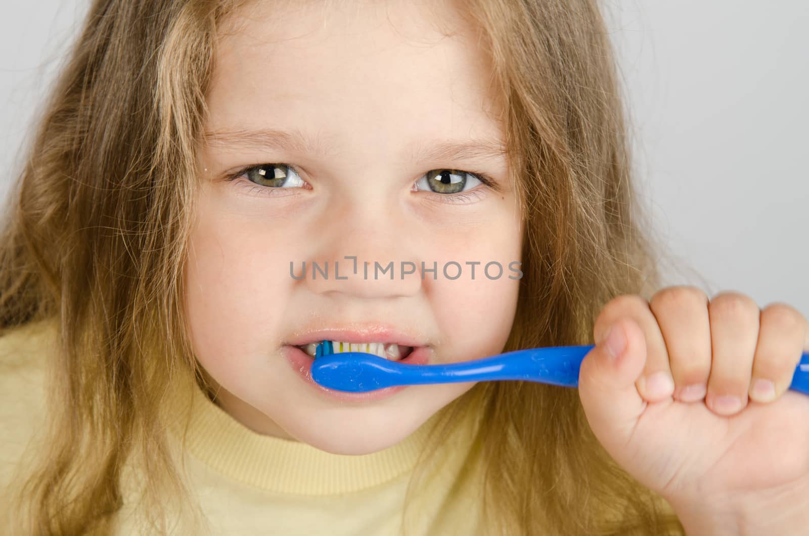 A girl of four years old brushing his teeth with a toothbrush