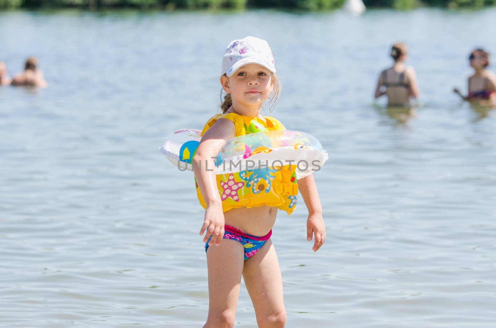 Four-year girl on a river beach wearing wearing the life jackets and circle