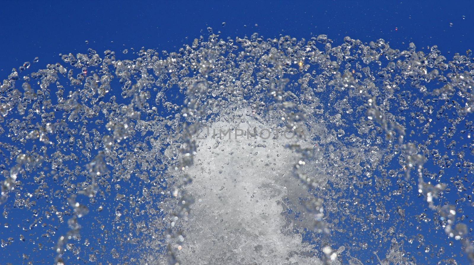 Fountain drops of pure water against a blue sky.