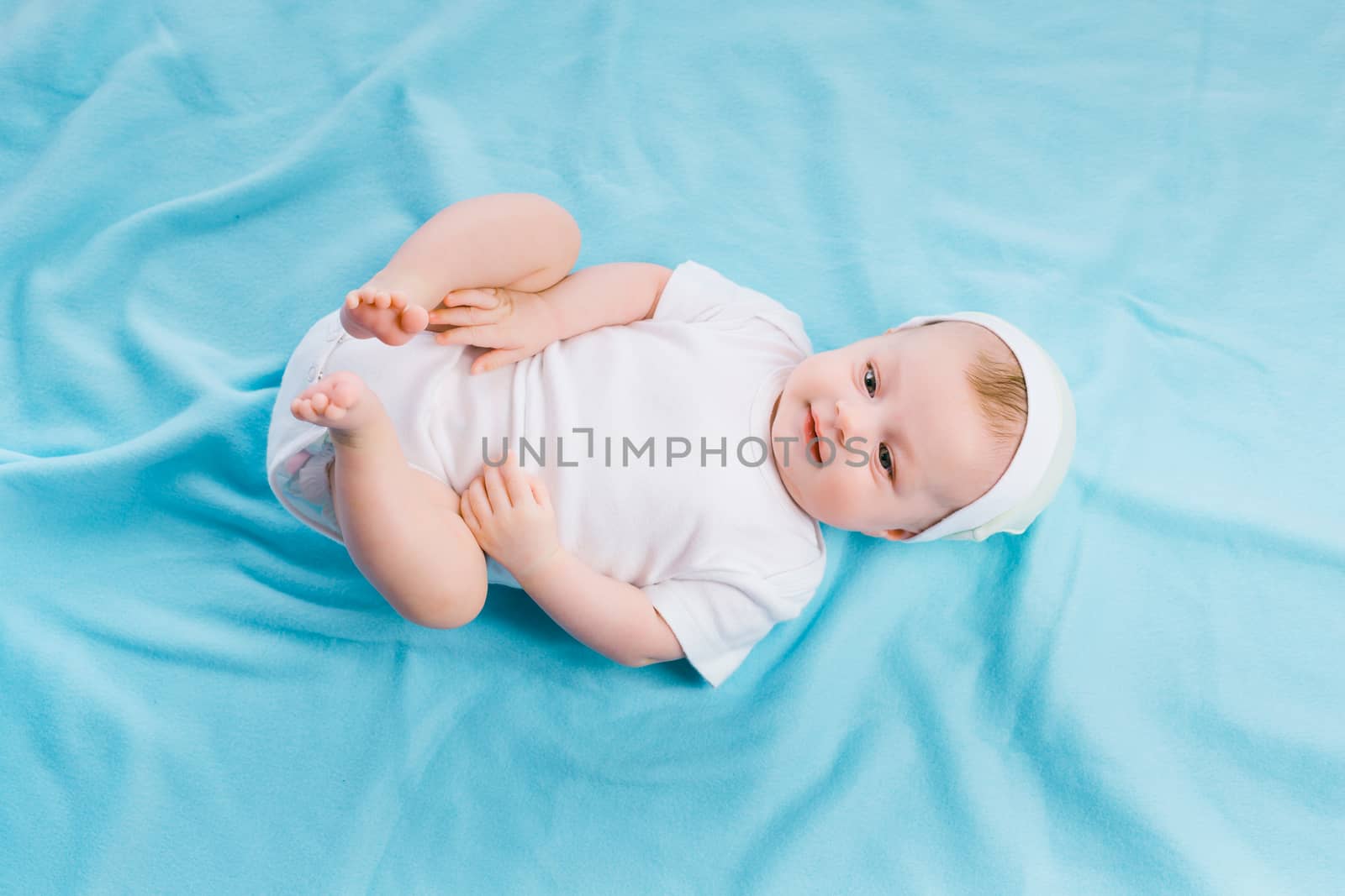 baby in cap lying on a blue blanket