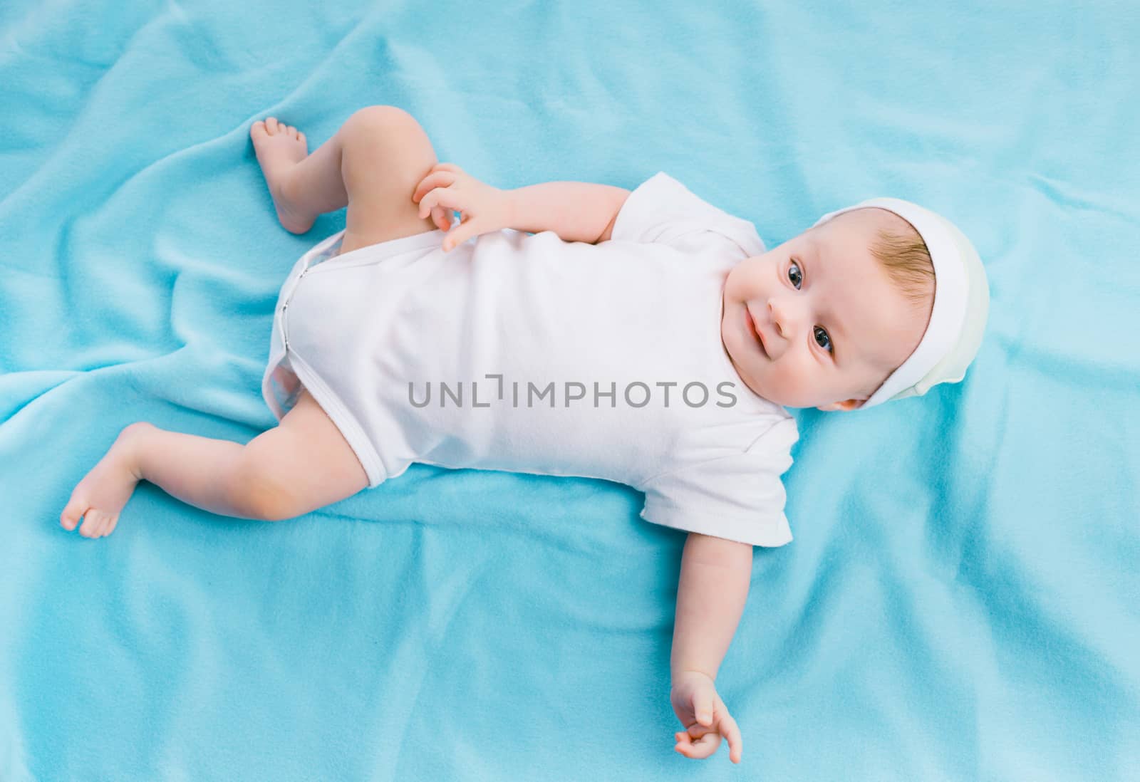 baby in cap lying on a blue blanket