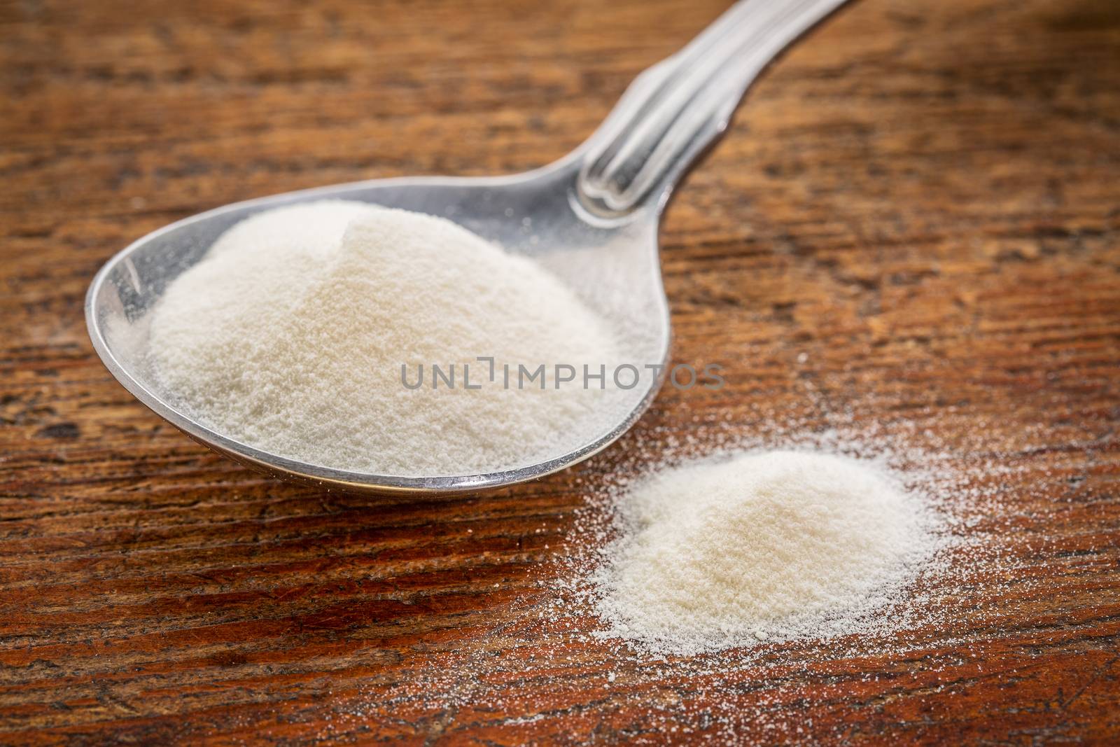 collagen protein powder on a tablespoon against rustic wood