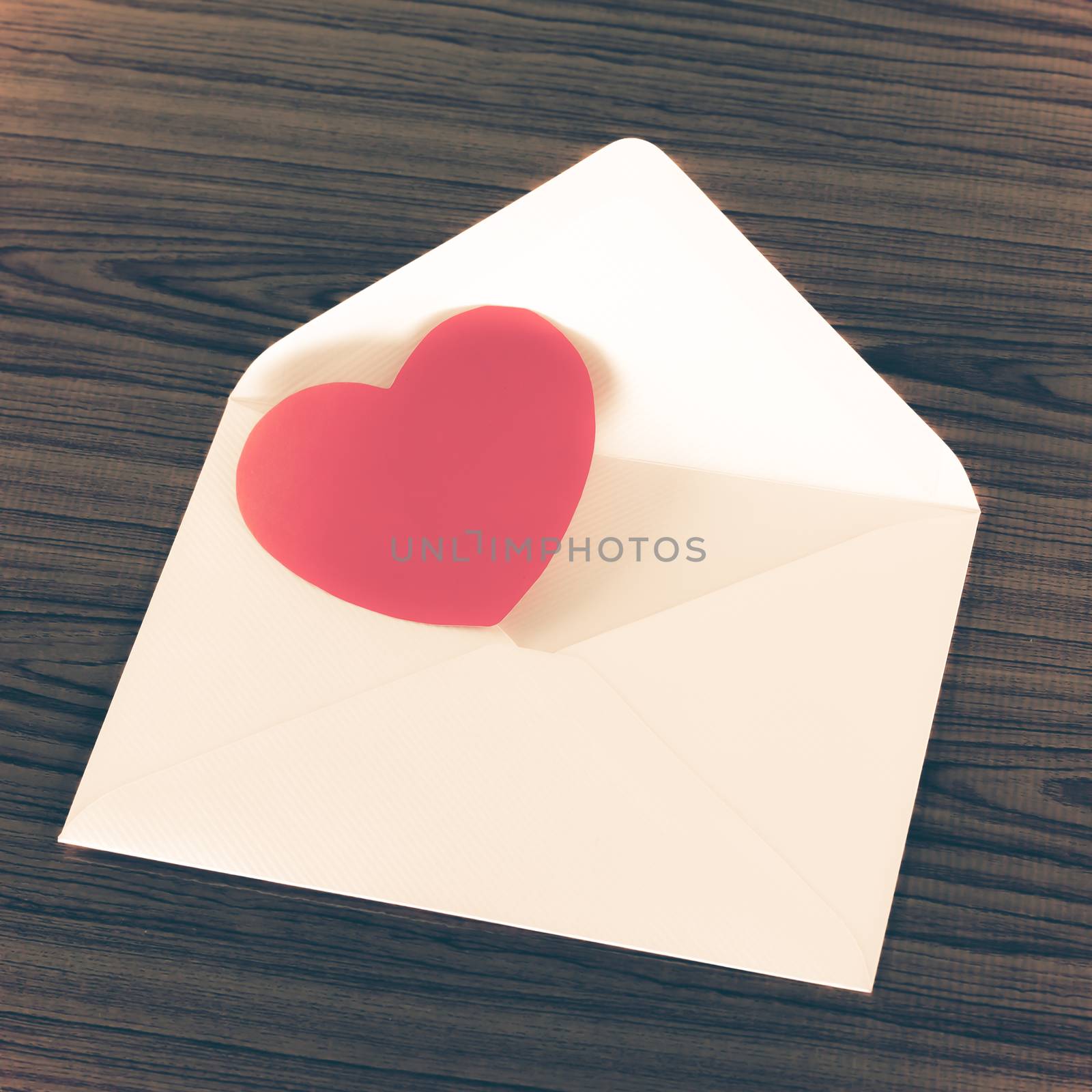 red heart with pink envelope on wooden background vintage style