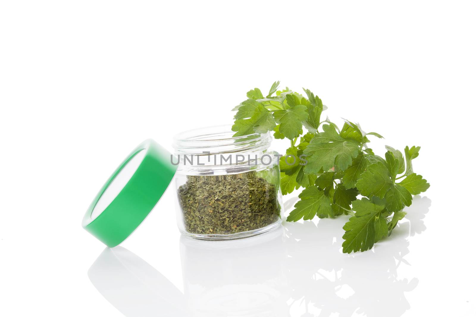 Fresh parsley leaves and dry parsley spice in glass jar isolated on white background. Culinary healthy aromatic herbs. Culinary arts, fines herbes.