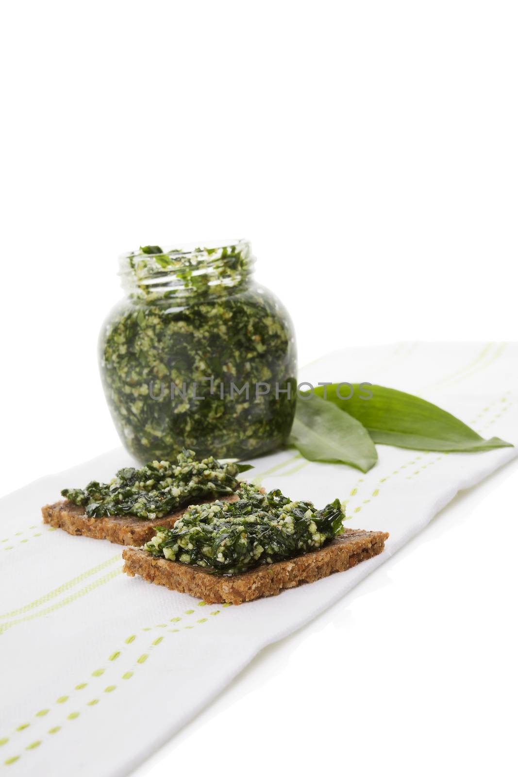 Culinary healthy eating, spring detox. Garlic pesto in glass jar with fresh wild garlic leaves isolated on white background. 