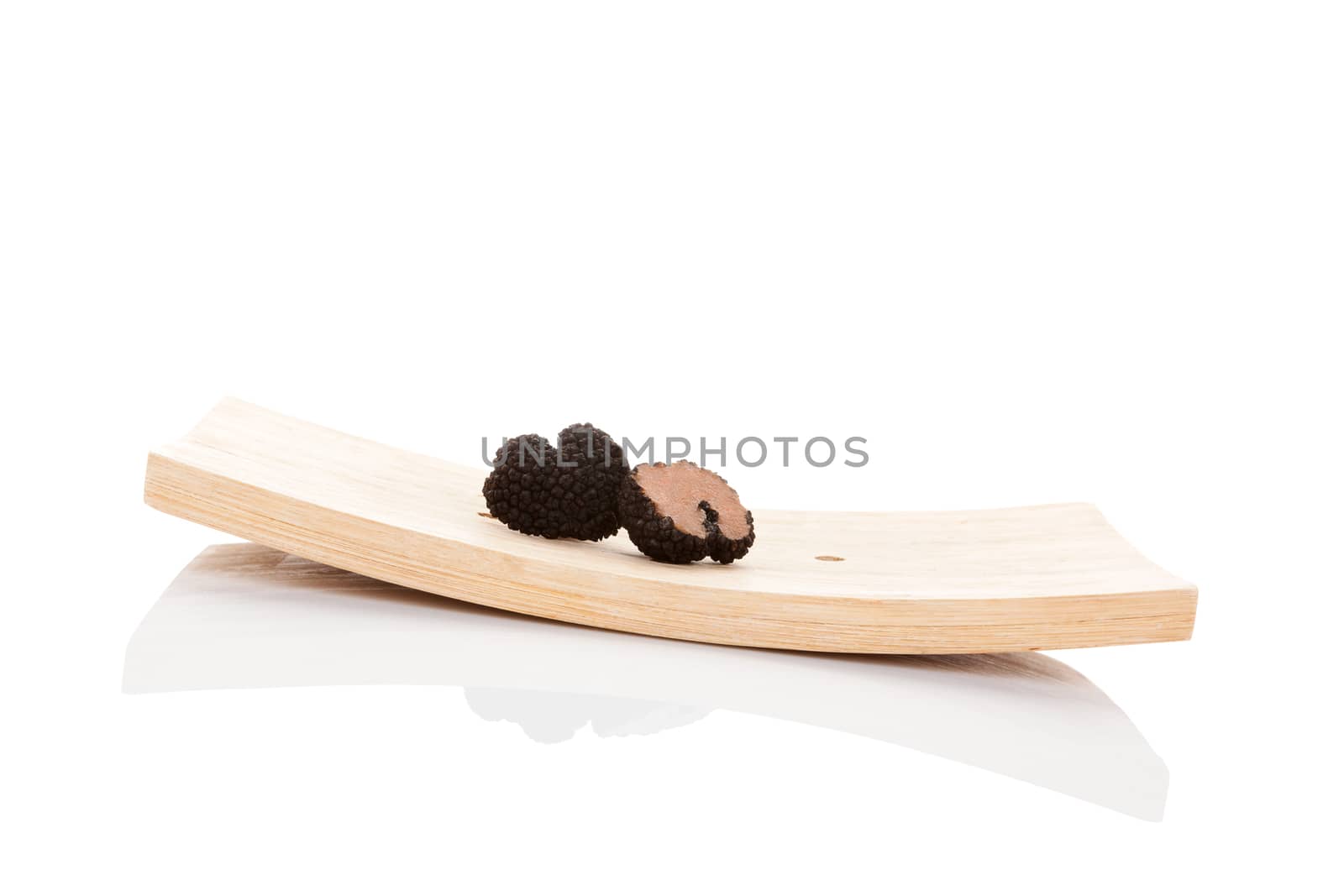 Truffles, rare mushrooms. Cut truffles on wooden plate isolated on white background. Luxurious culinary cooking ingredients. 