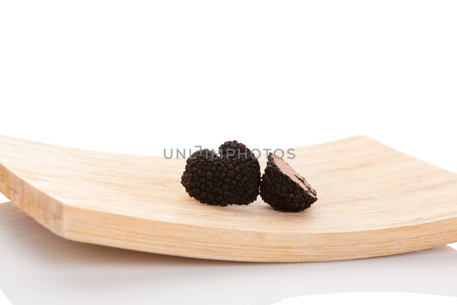 Truffles, rare mushrooms. Cut truffles on wooden plate isolated on white background. Luxurious culinary cooking ingredients. 