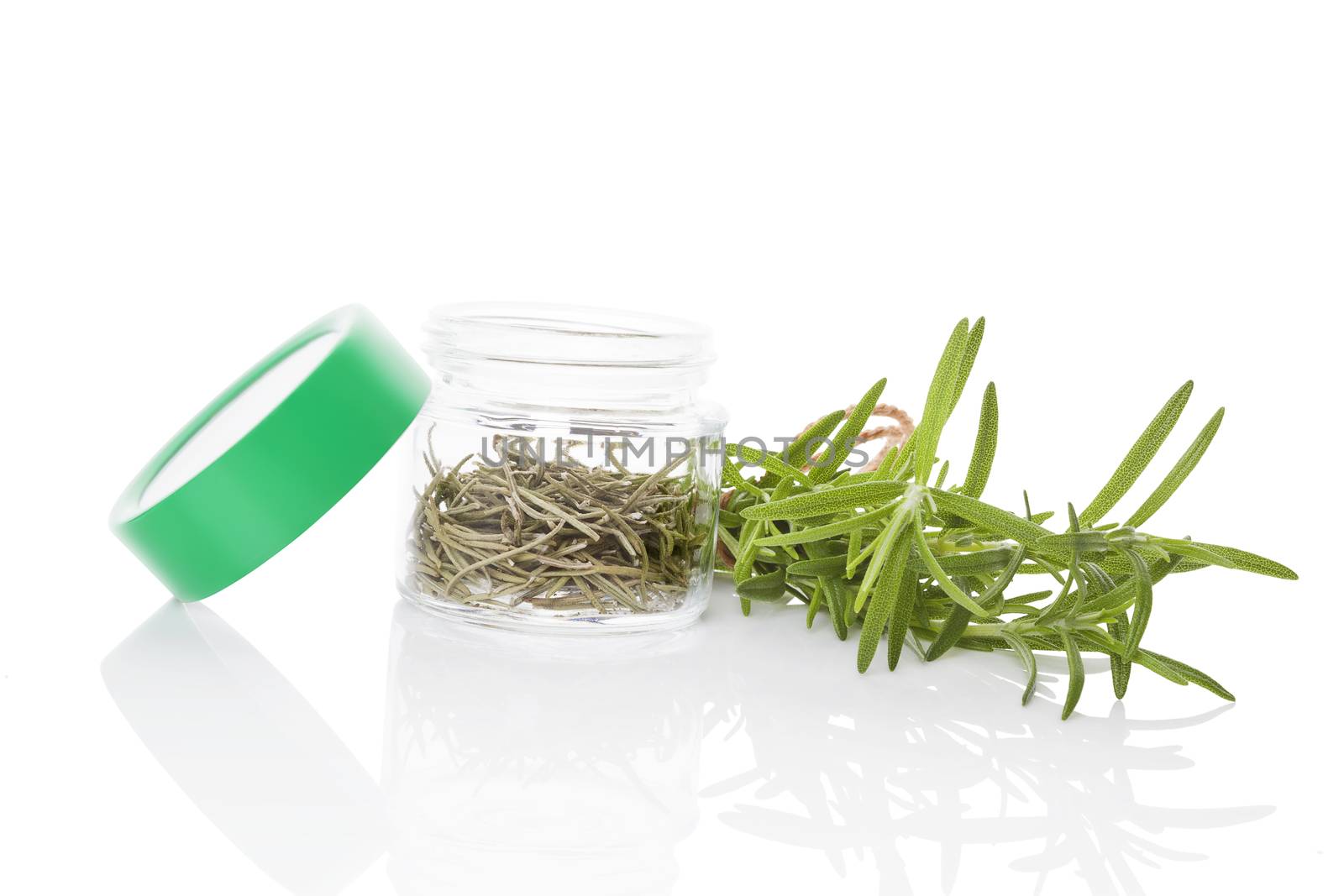 Fresh rosemary herbs and dry rosemary spice in glass jar isolated on white background. Culinary healthy aromatic herbs. Culinary arts.