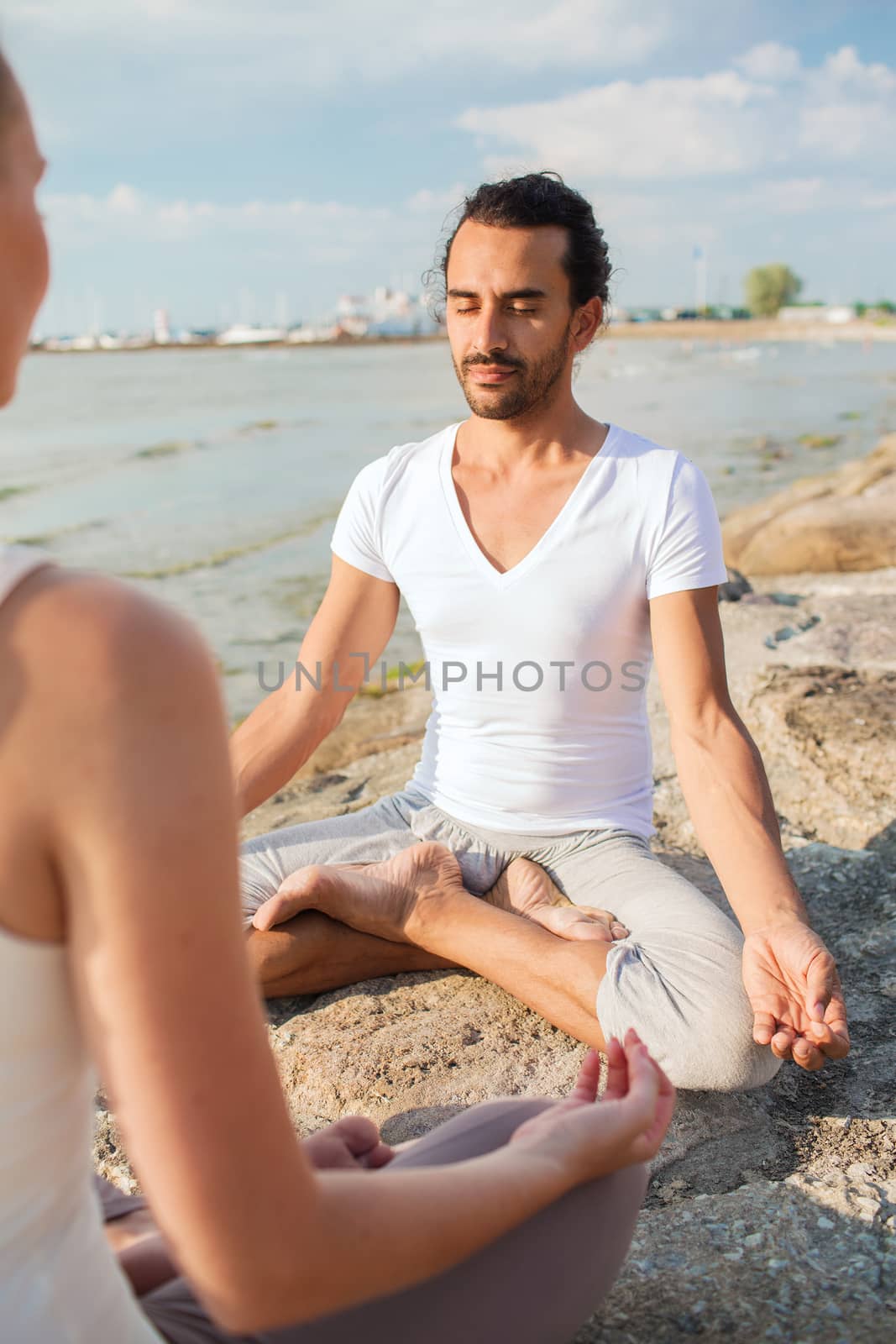 smiling couple making yoga exercises outdoors by dolgachov