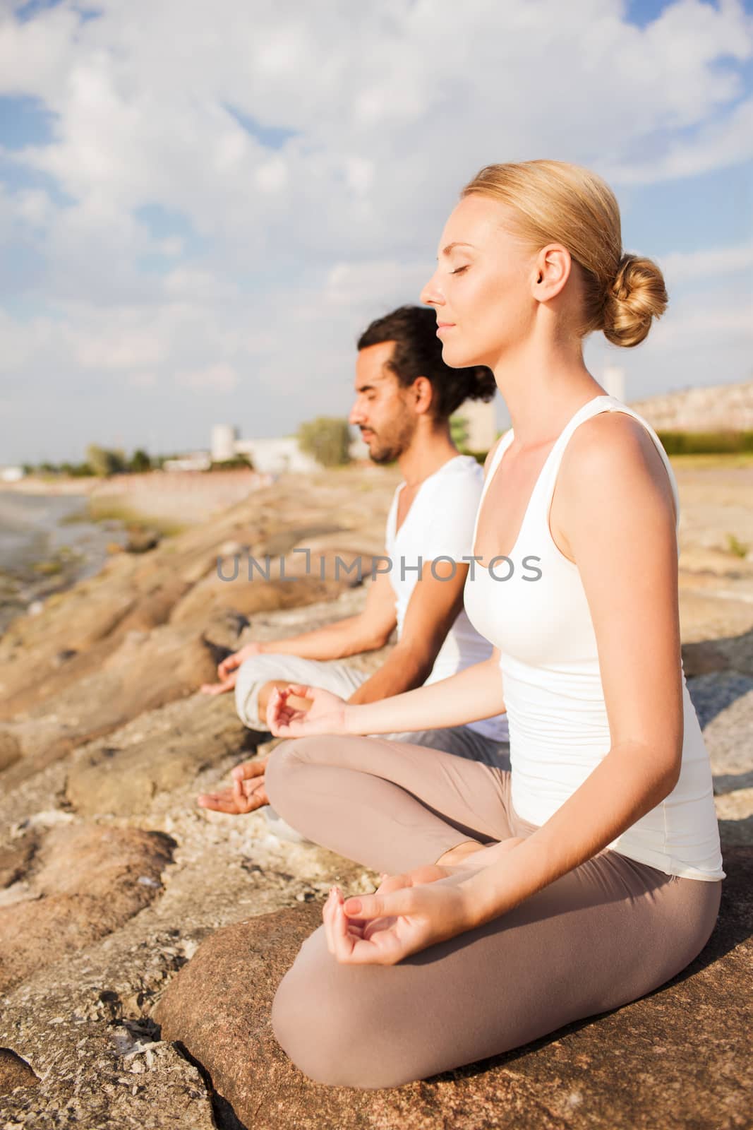 smiling couple making yoga exercises outdoors by dolgachov