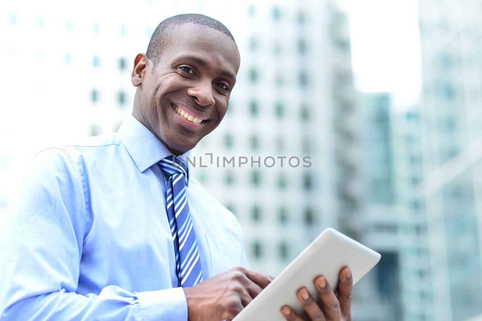 Businessman posing with digital tablet by stockyimages