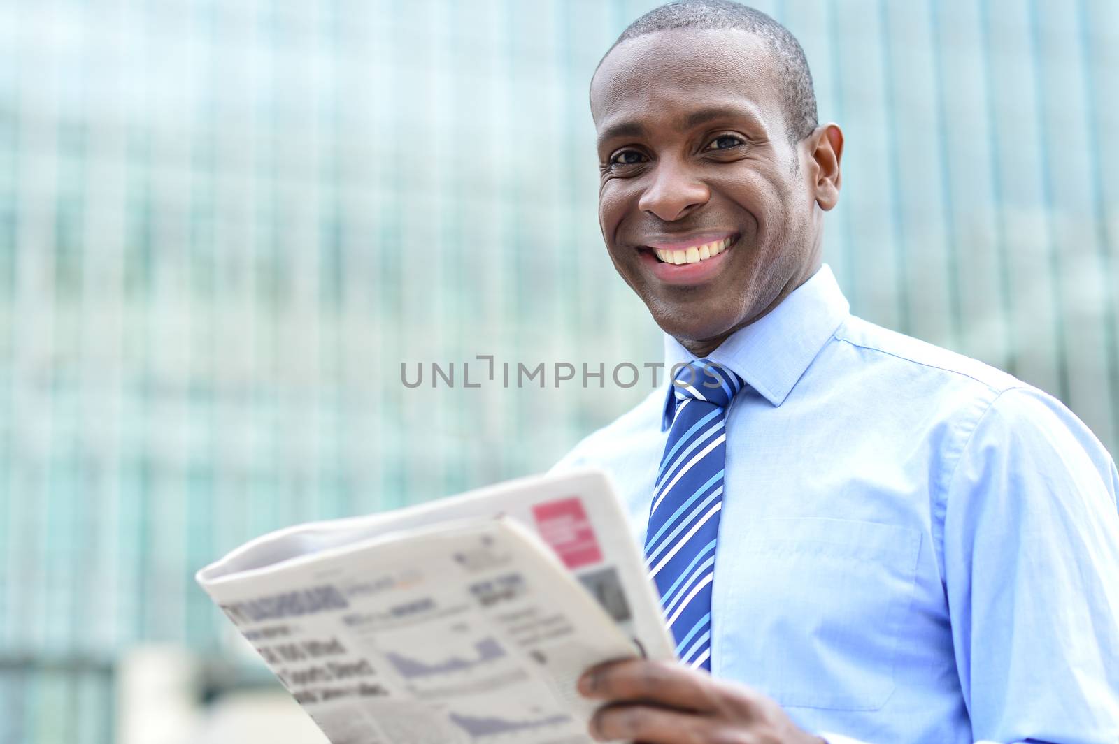 Corporate male smiling with magazine at outdoors