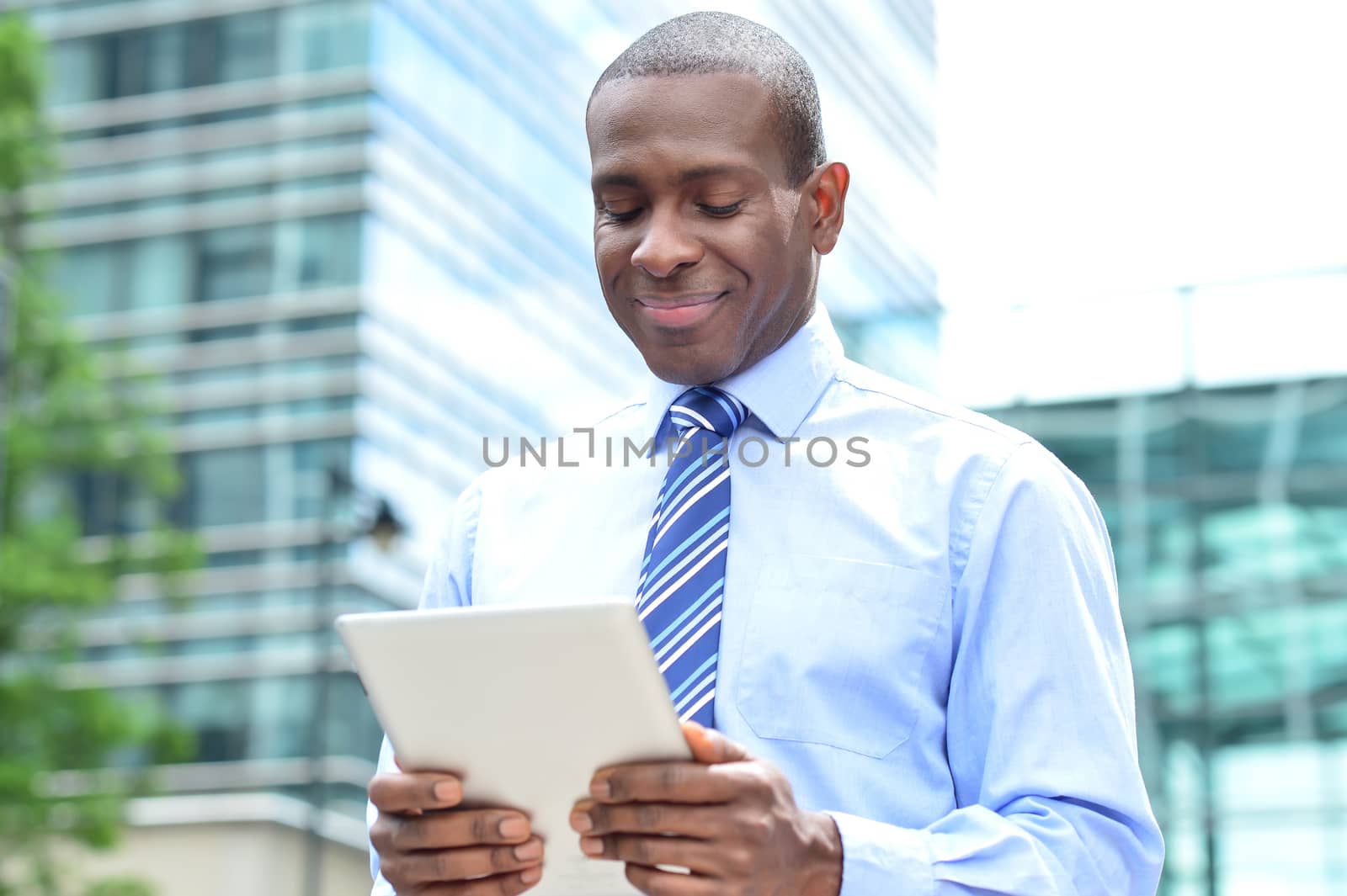 Happy businessman checking mails in tablet