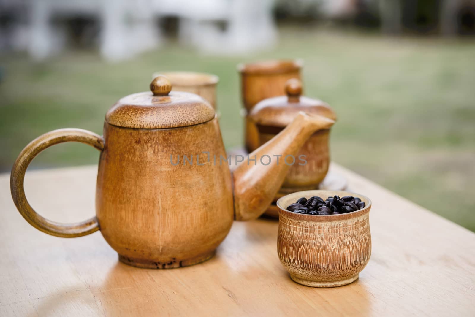 Coffee beans, cup of coffee and teapot on wooden desk. Set of cafe