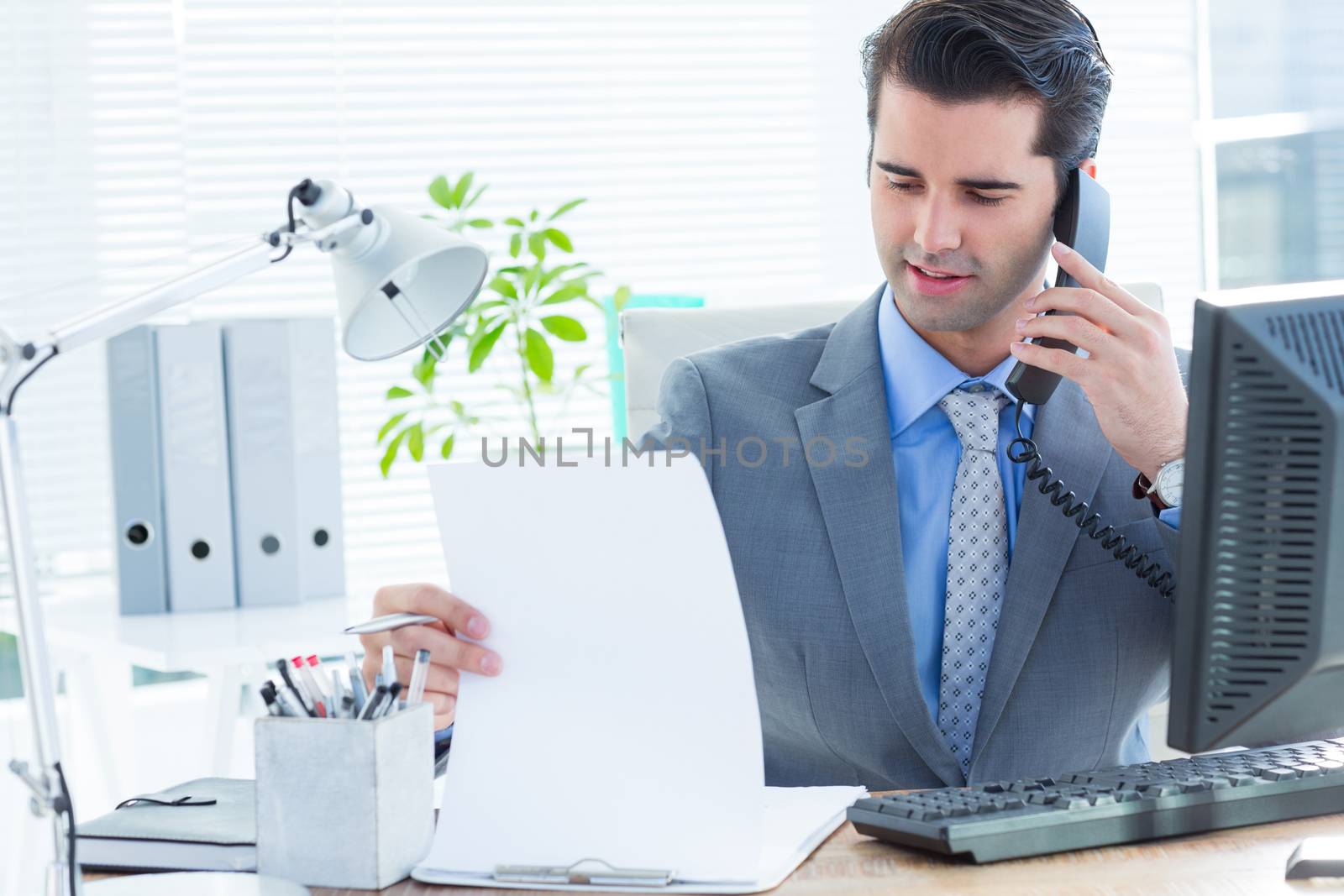 Professional businessman checking at his notebook while on the phone