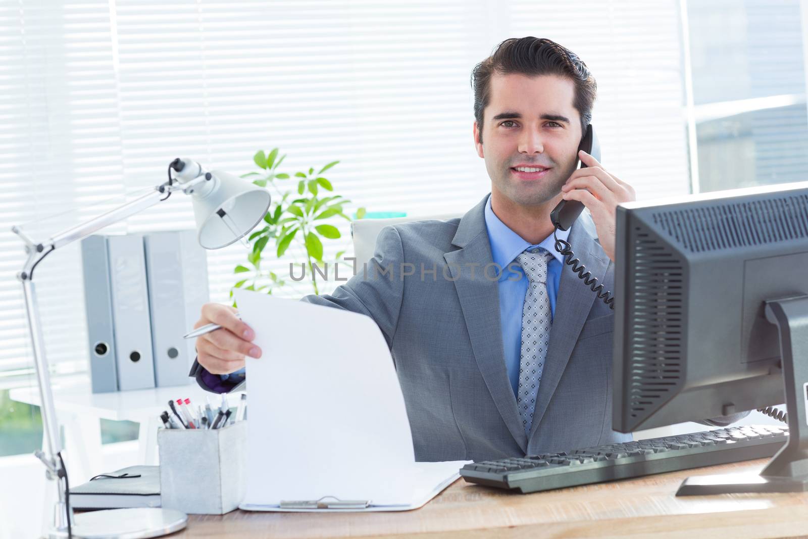 Portrait of a professional businessman checking at his notebook while on the phone