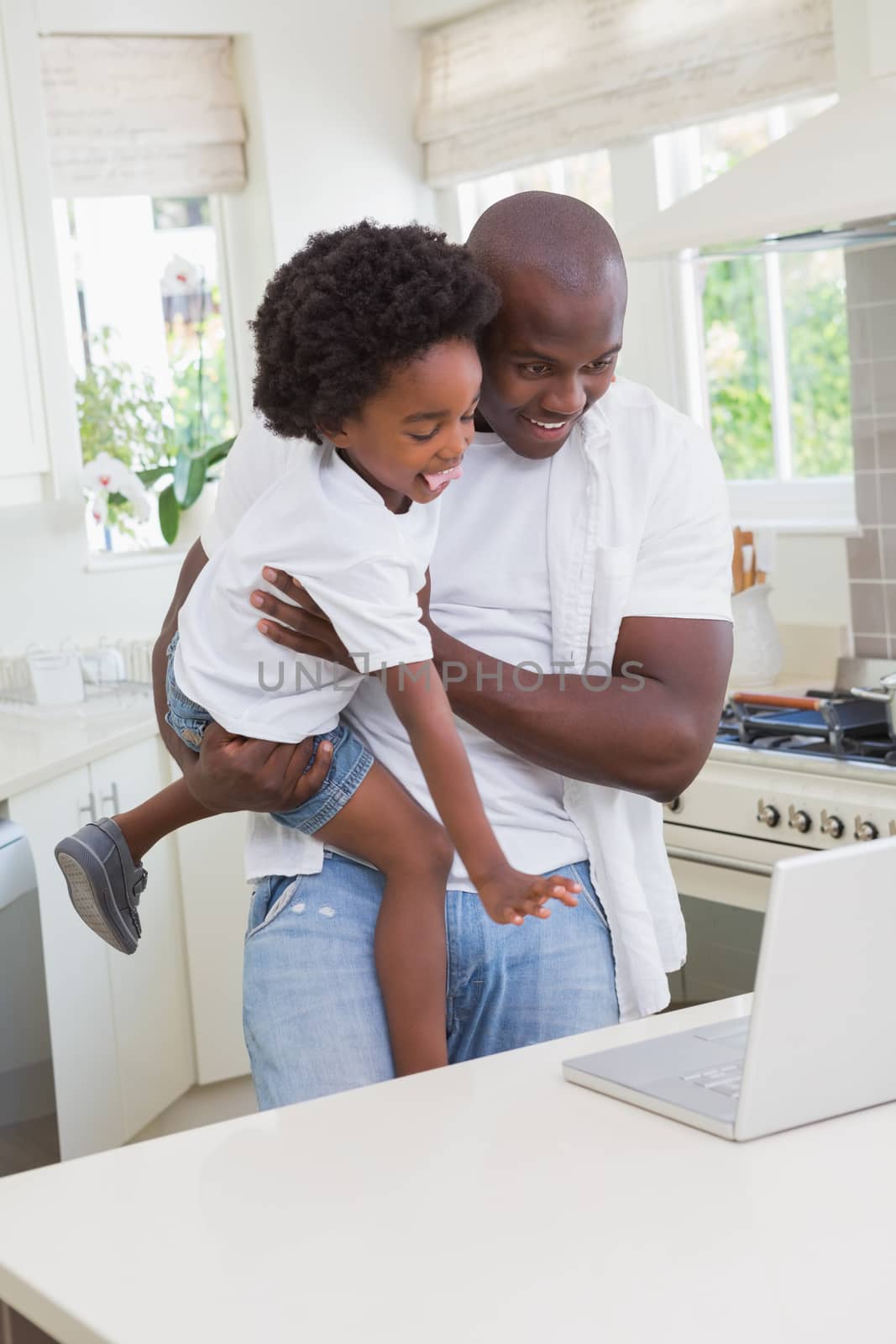 Father and son using laptop on the couch at home in living room