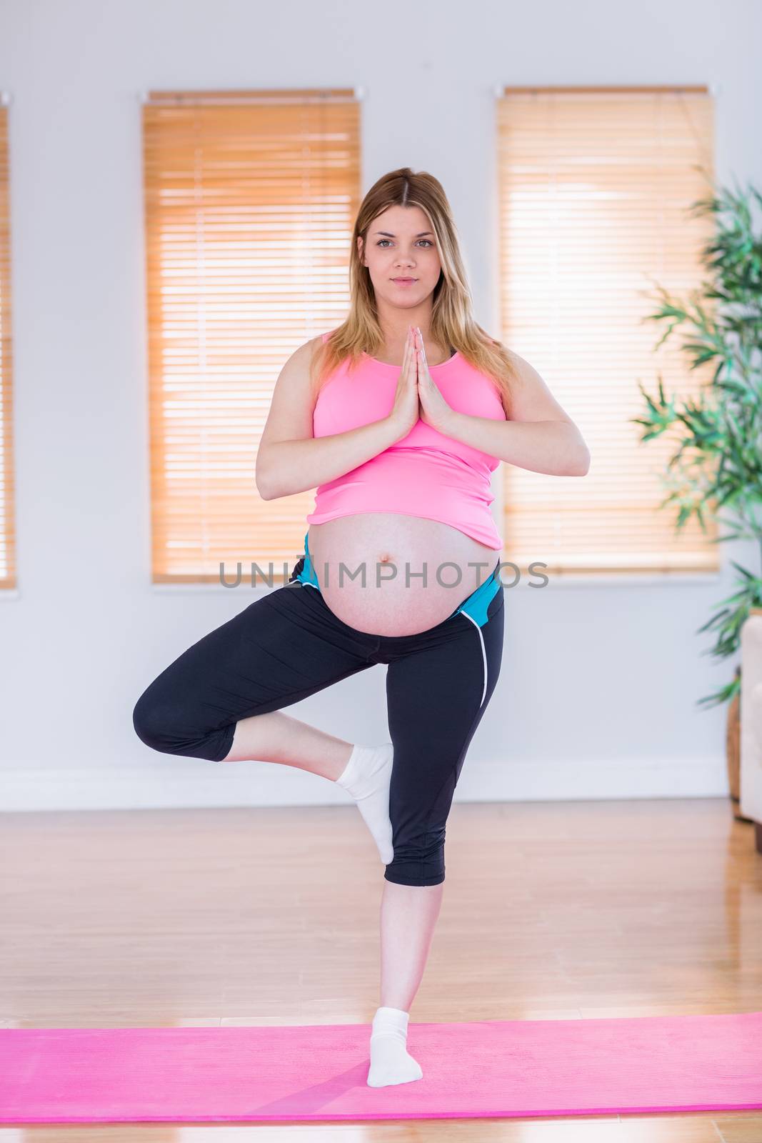 Pregnant woman doing yoga on exercise mat at home