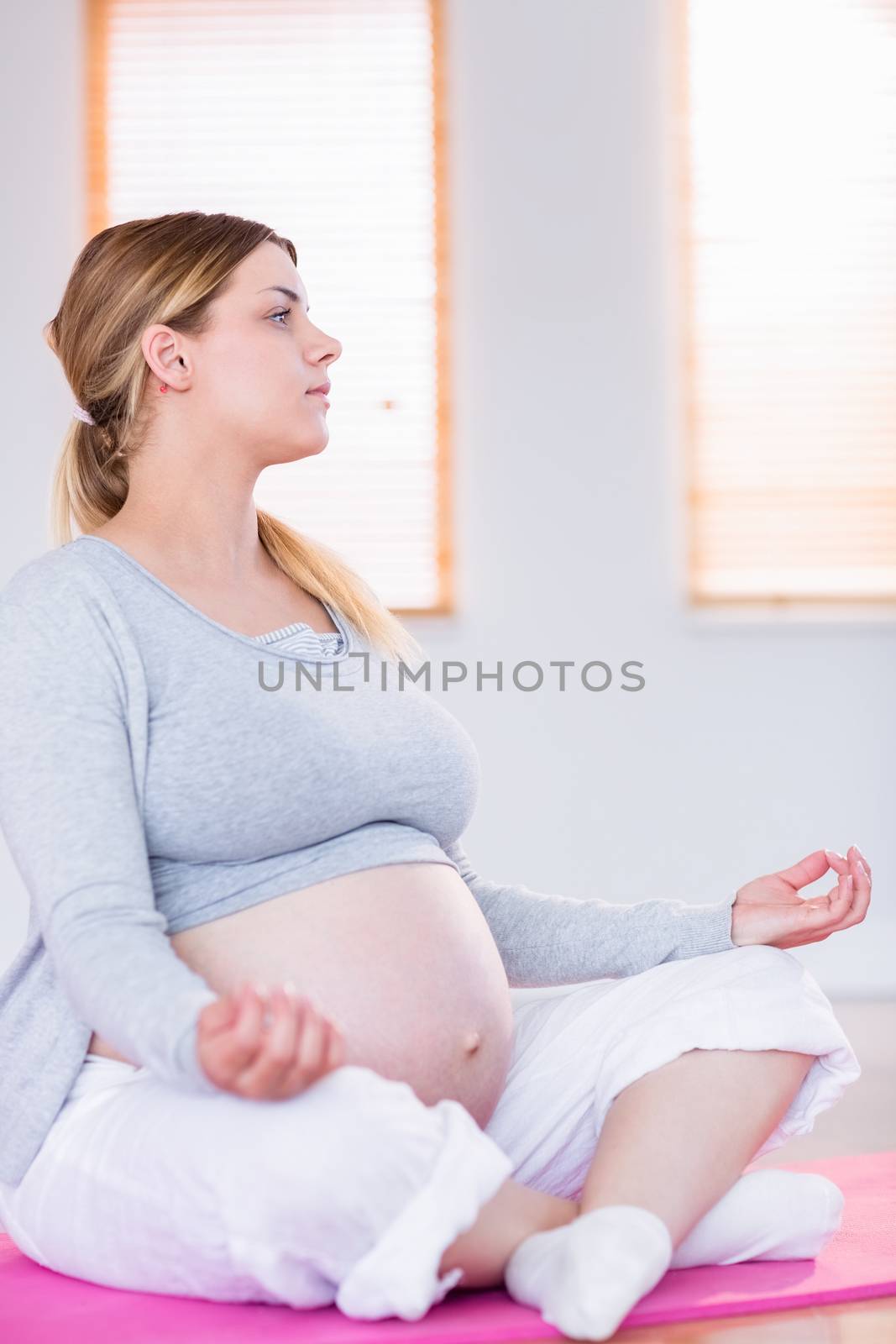 Pregnant woman doing yoga on exercise mat at home