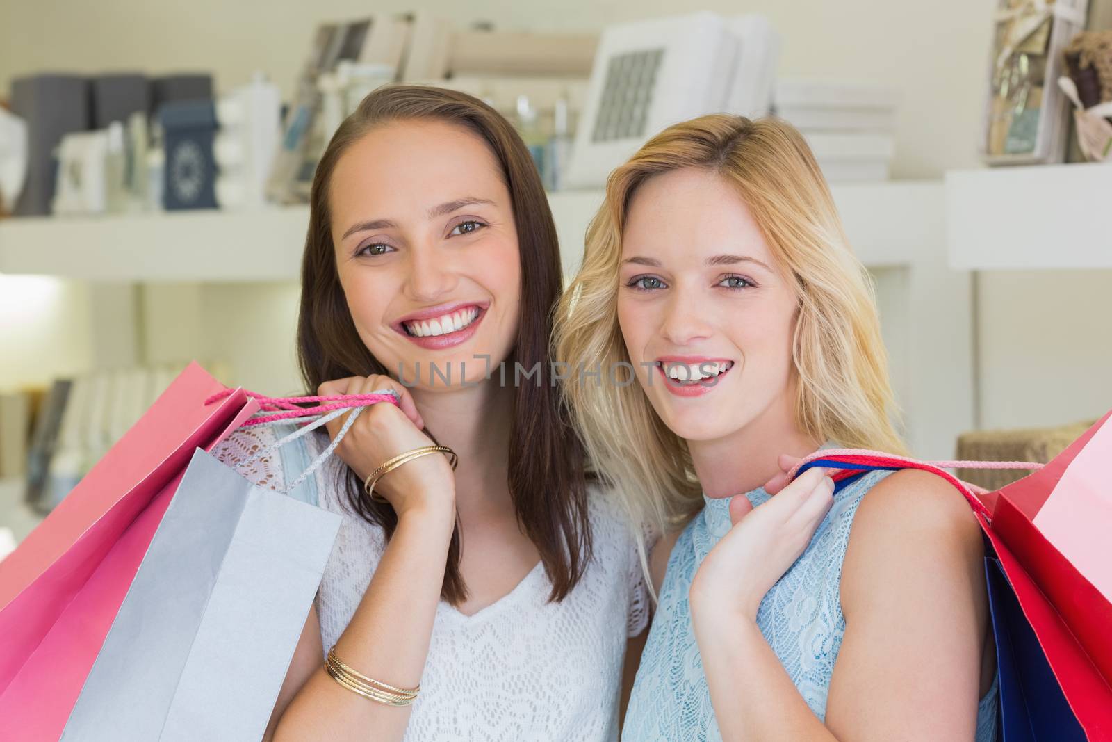 Happy women smiling at camera with shopping bags in a beauty salon