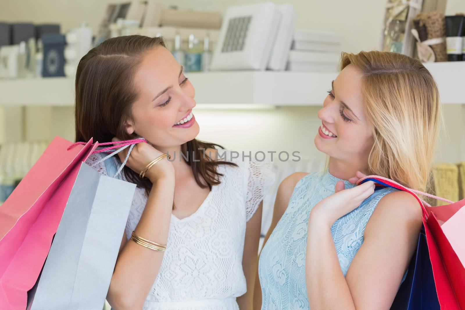 Happy women looking at each other with shopping bags in a beauty salon