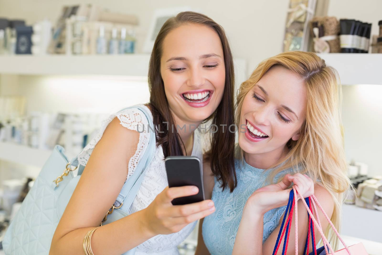 Happy friends women looking at smartphone in a beauty salon