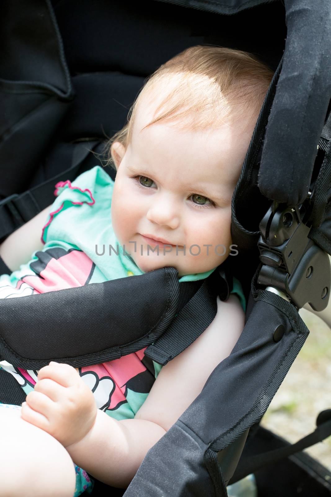lose up Portrait of a Cute White Blond Baby girl on his Stroller, Looking Into the Distance.