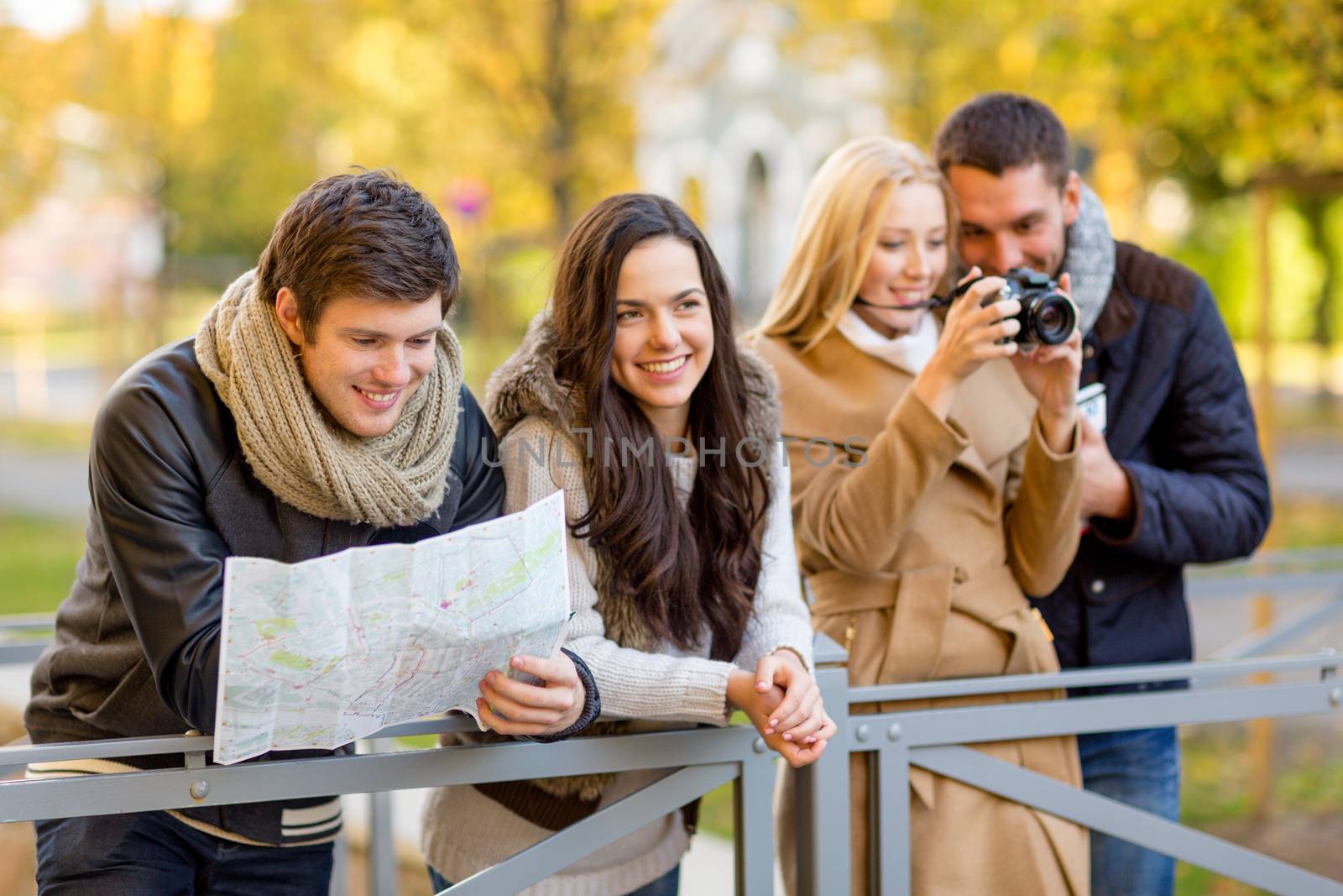 travel, vacation, technology, tourism and friendship concept - group of smiling friends with digital photo camera and map in city park