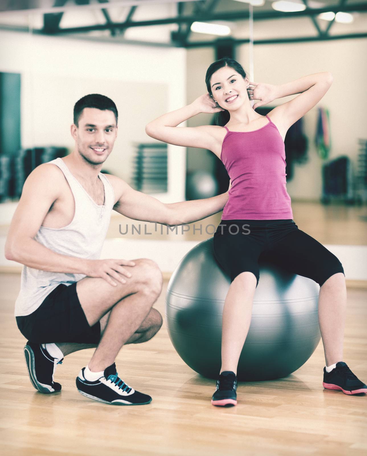 fitness, sport, training, gym and lifestyle concept - male trainer with woman doing crunches on the ball