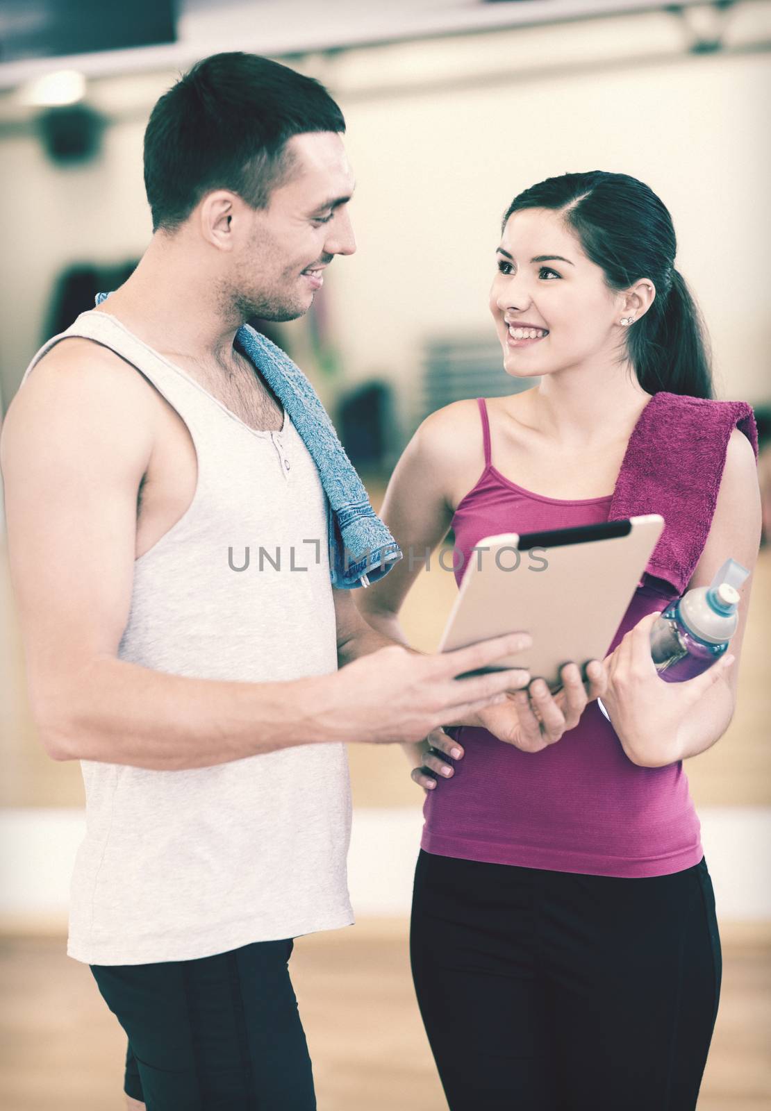 two smiling people with tablet pc in the gym by dolgachov