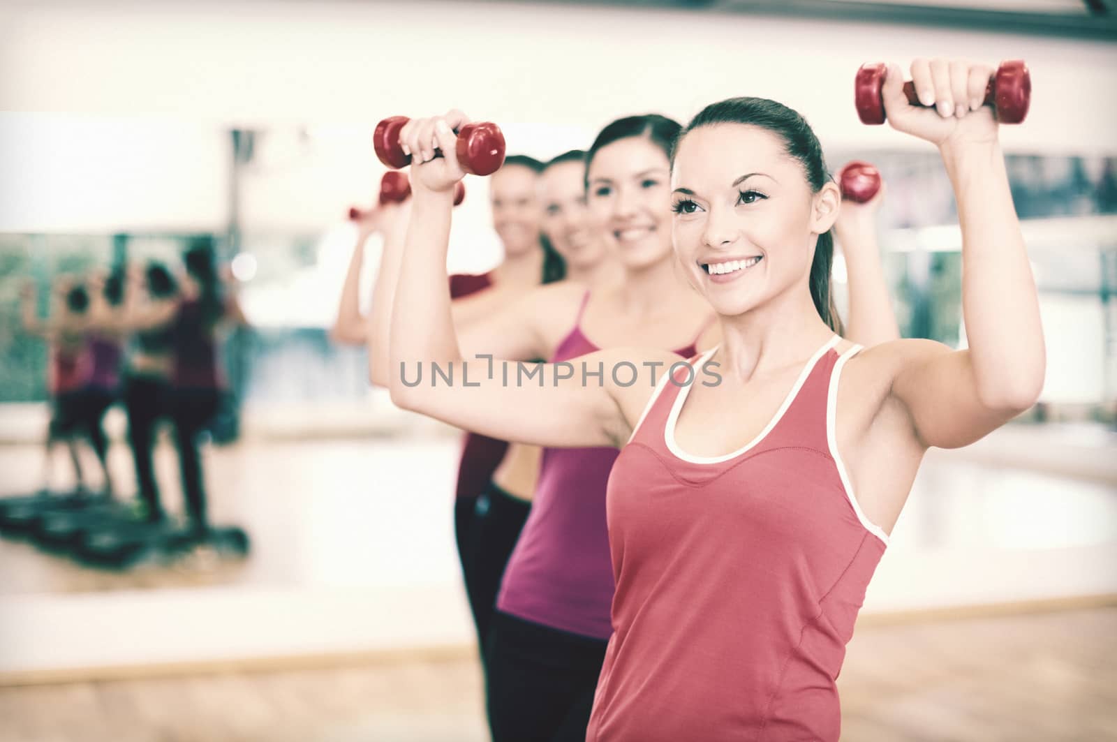 group of smiling people working out with dumbbells by dolgachov