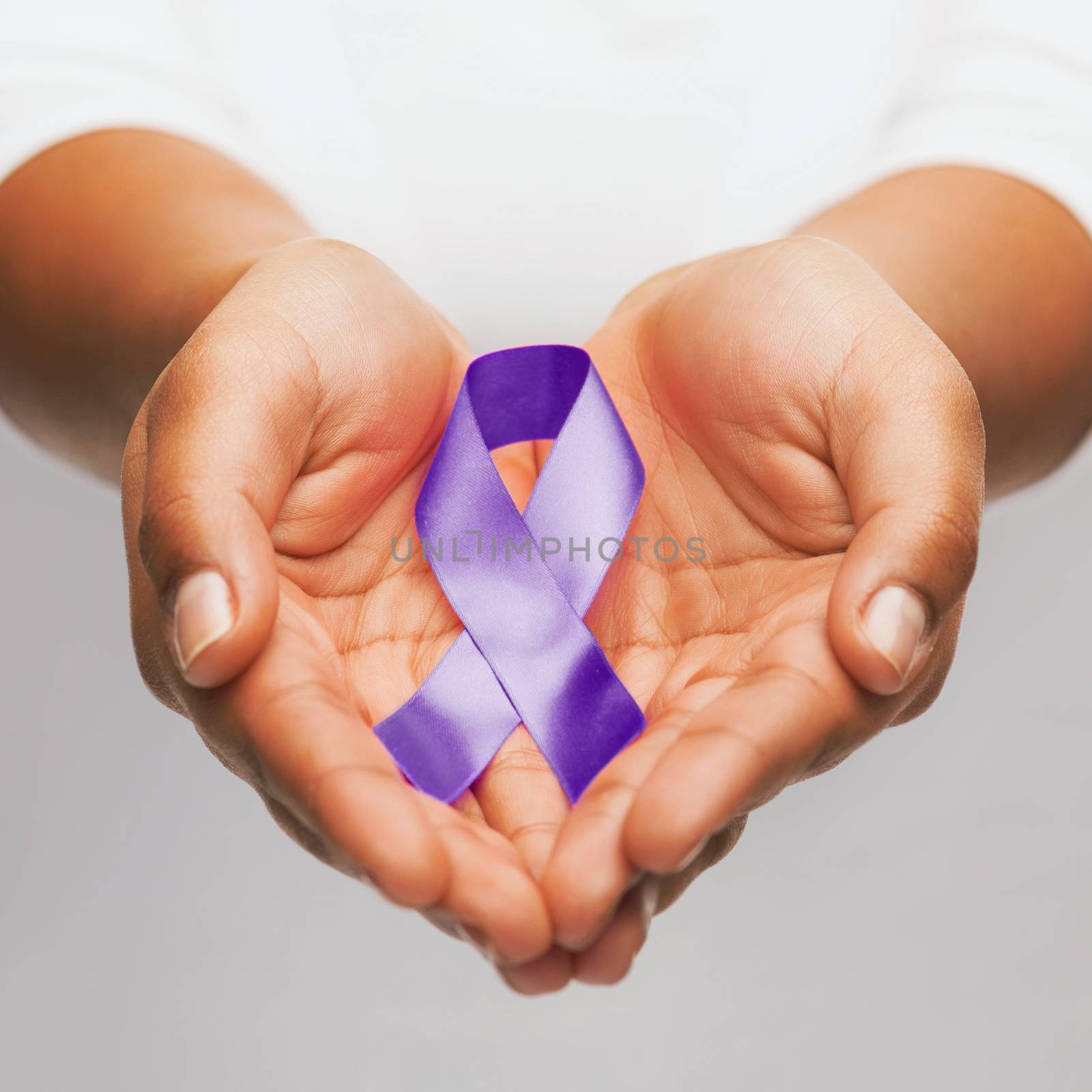 healthcare and social problem concept - womans hands holding purple domestic violence awareness ribbon