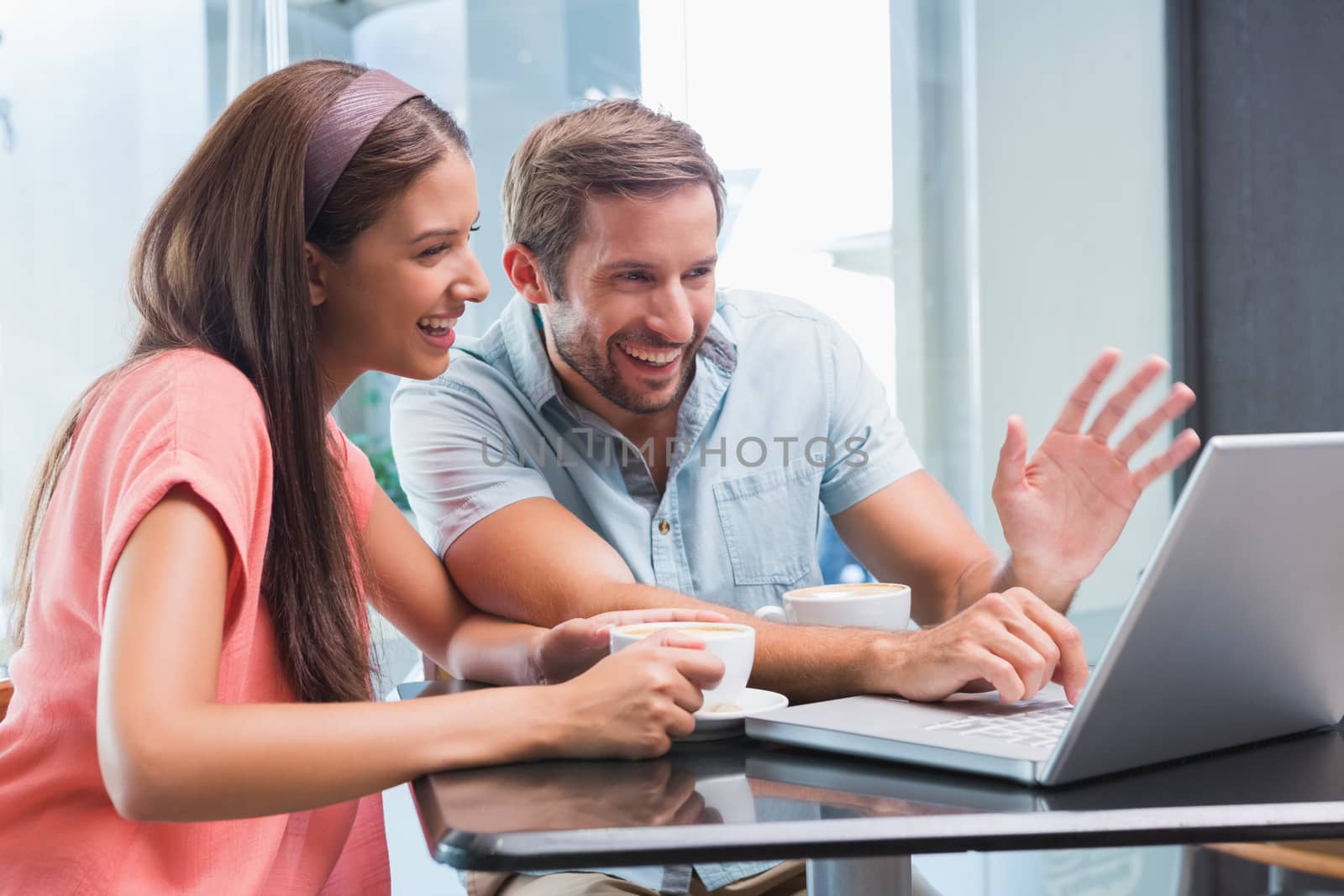 Young happy couple looking at a laptop in the cafe