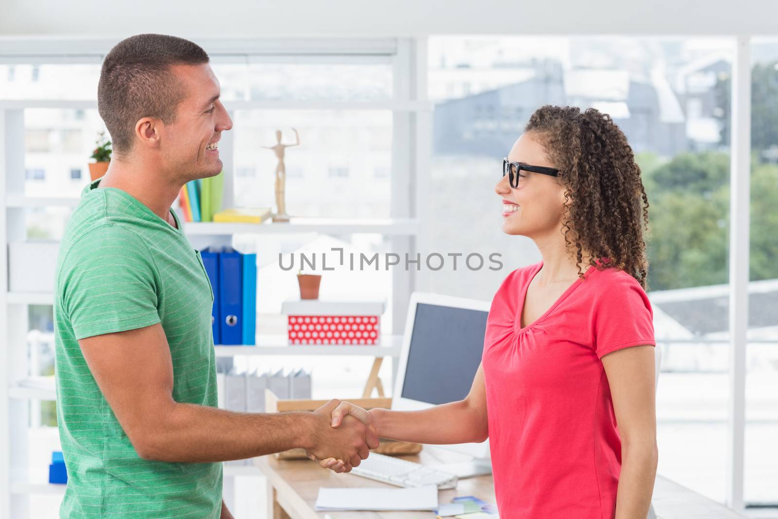 Casual business partners shaking their hands by Wavebreakmedia