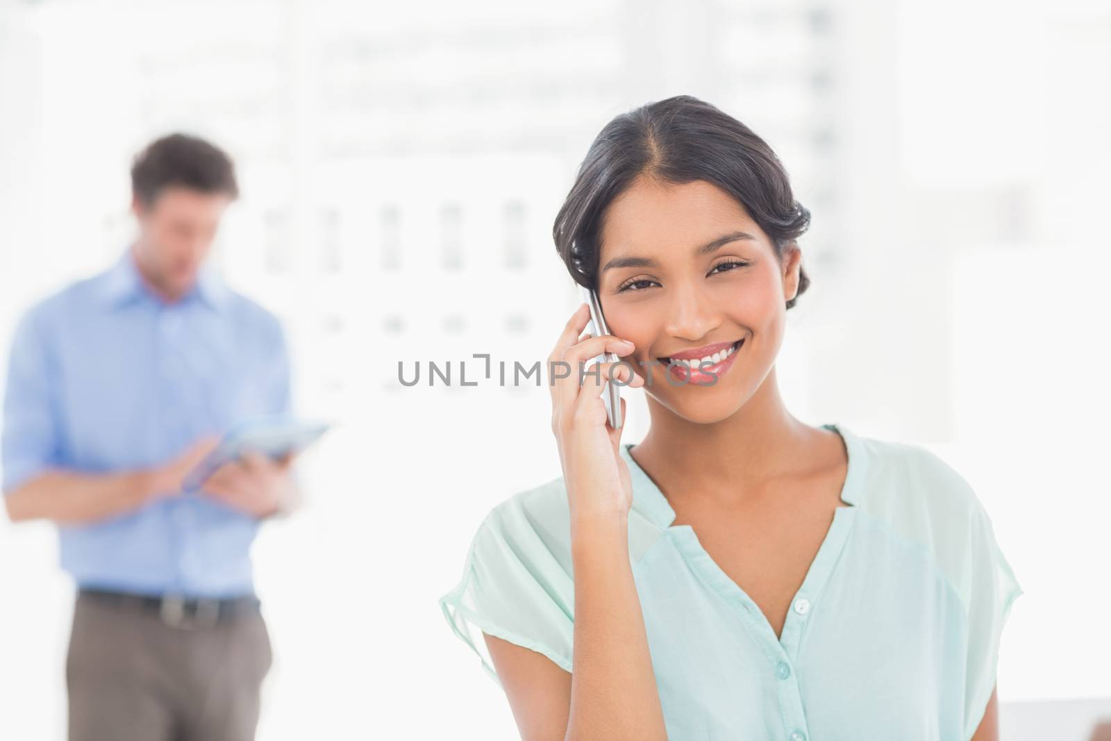 Two casual business people using digital tablet and telephone