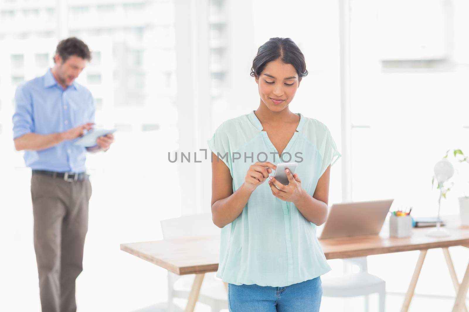 Two casual business people using digital tablet and telephone