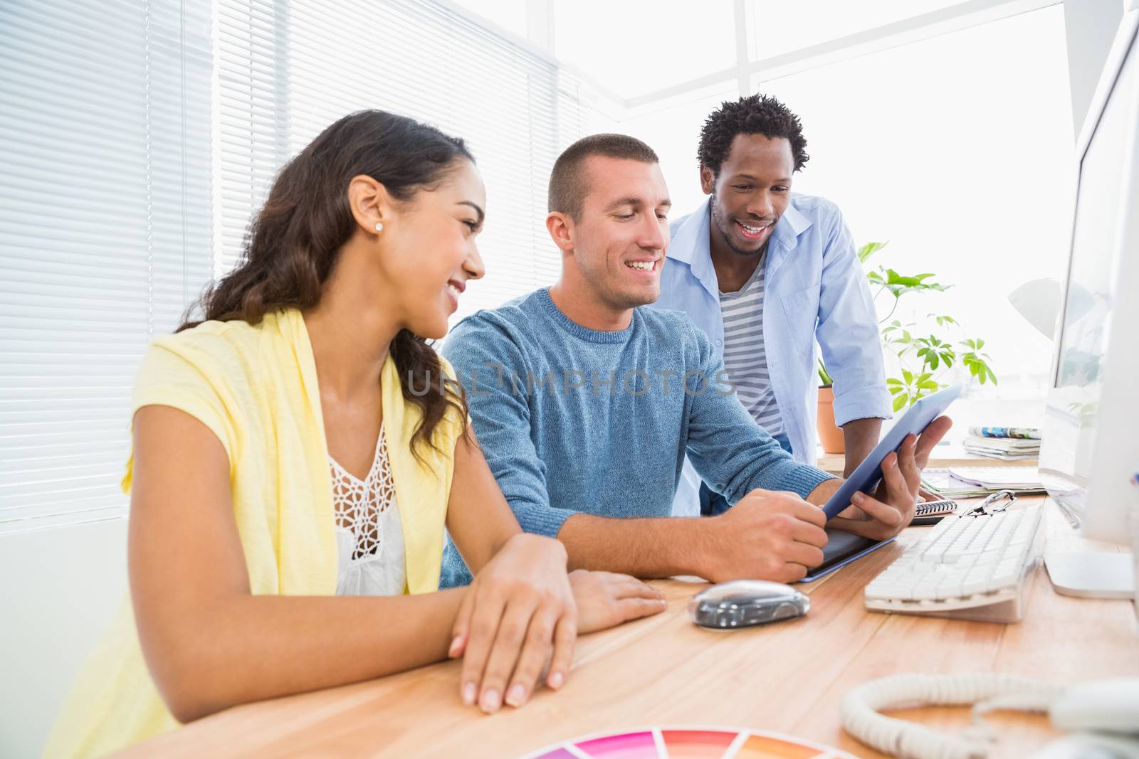 Smiling coworkers using tablet computer together by Wavebreakmedia