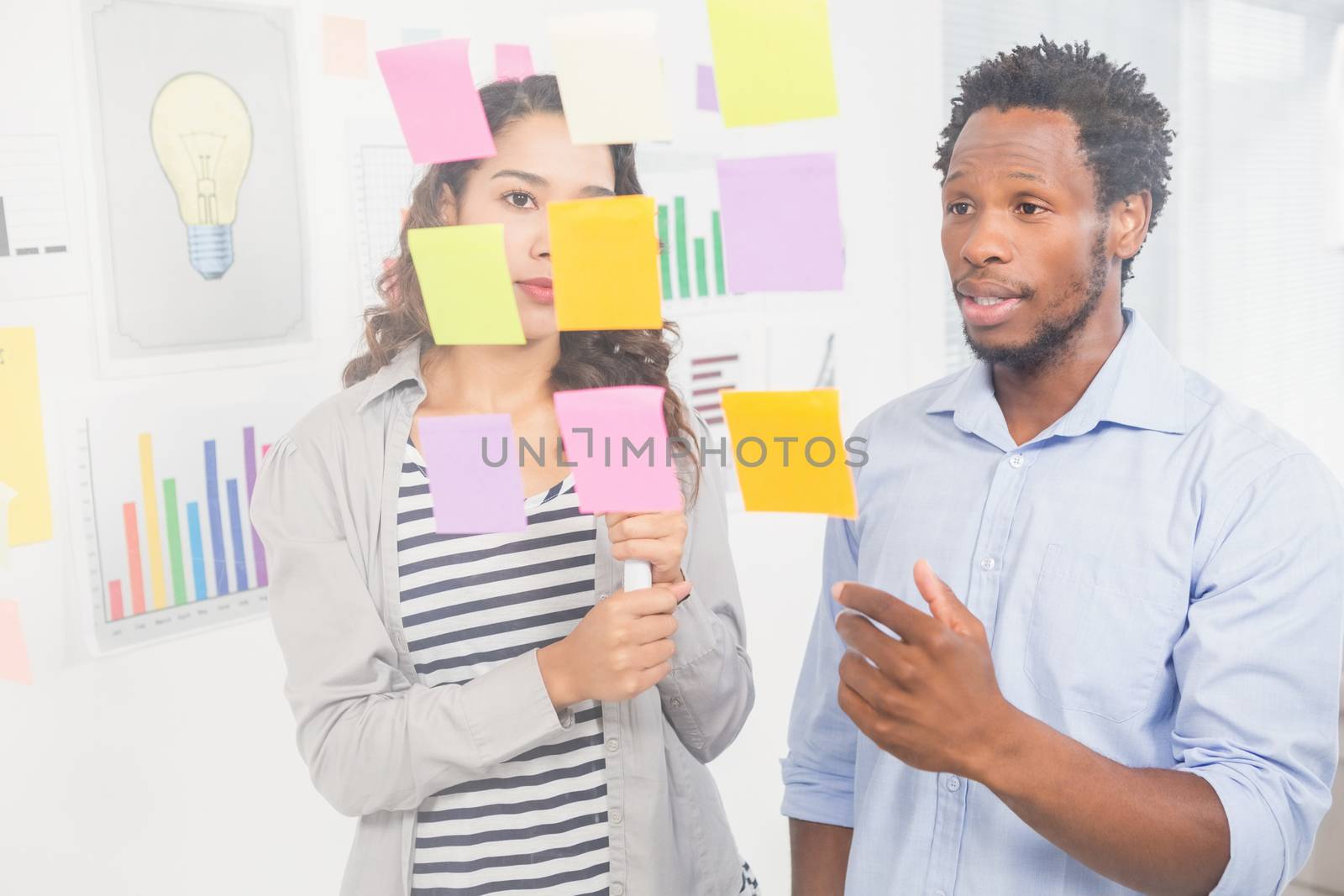 Young creative business people at the office looking at sticky notes and talking to each other