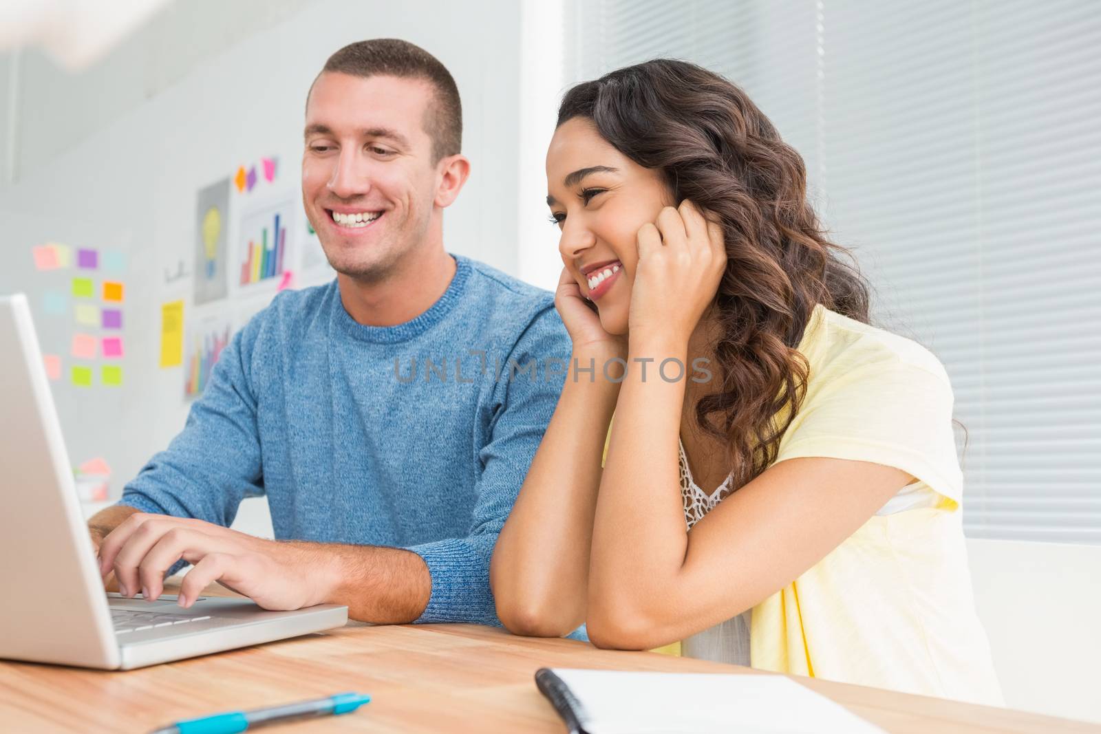 Smiling colleagues working together with laptop in the office