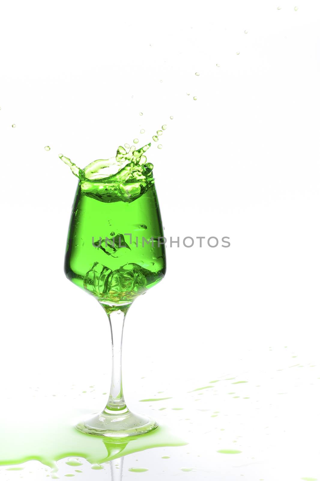 Stemmed champagne glass with liquor splashing out, isolated on white background