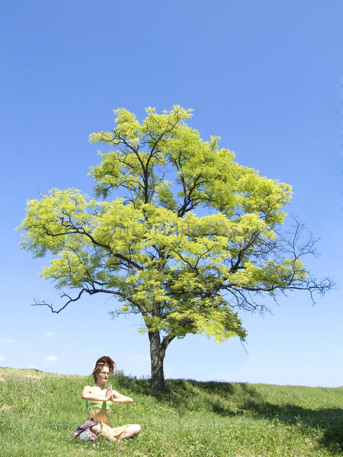 women meditate under tree by fadeinphotography