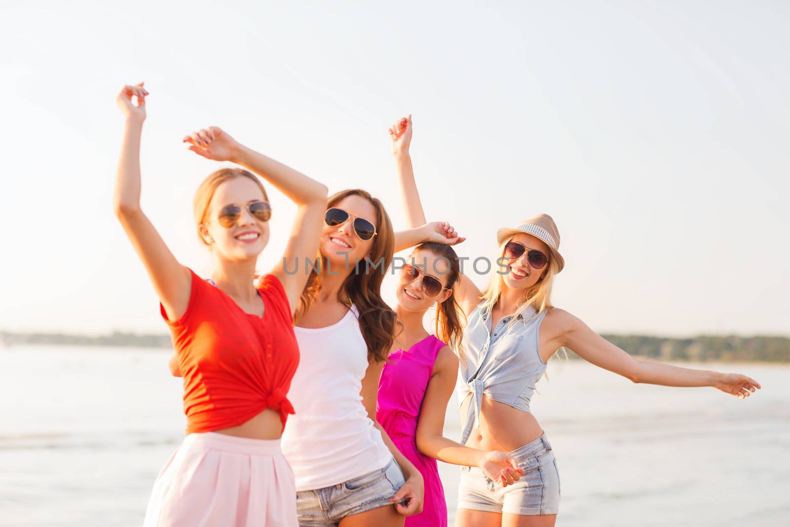 group of smiling women dancing on beach by dolgachov