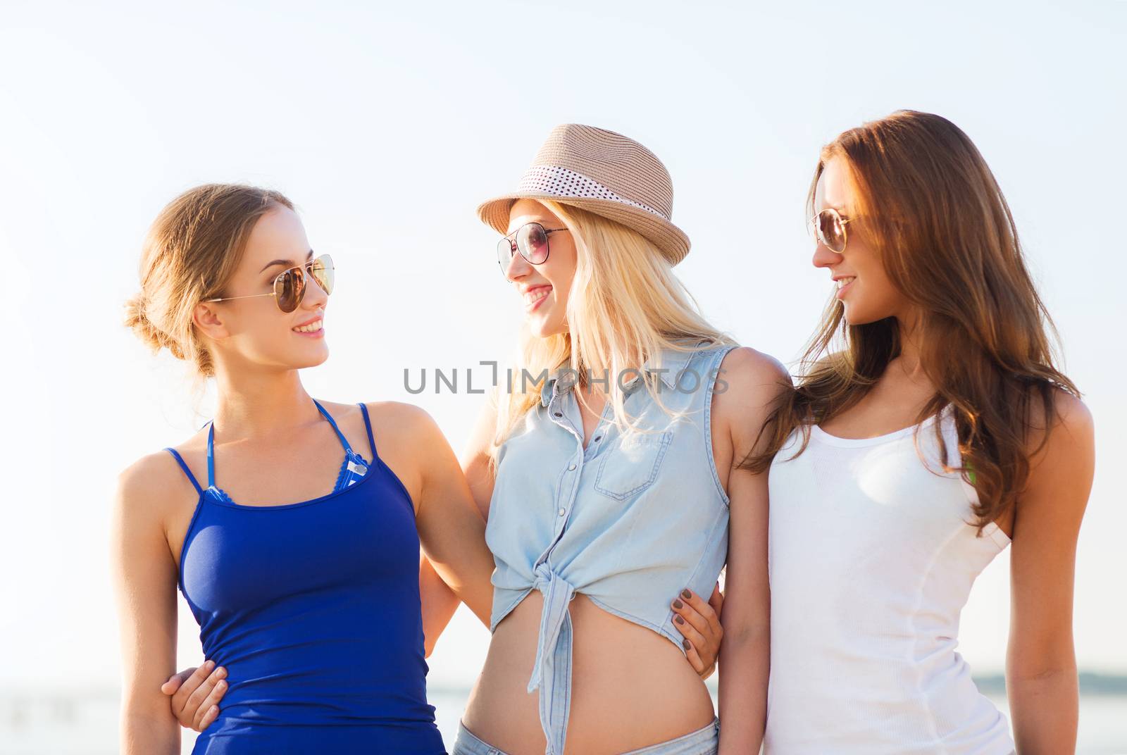 summer vacation, holidays, travel and people concept - group of smiling young women in sunglasses and casual clothes on beach