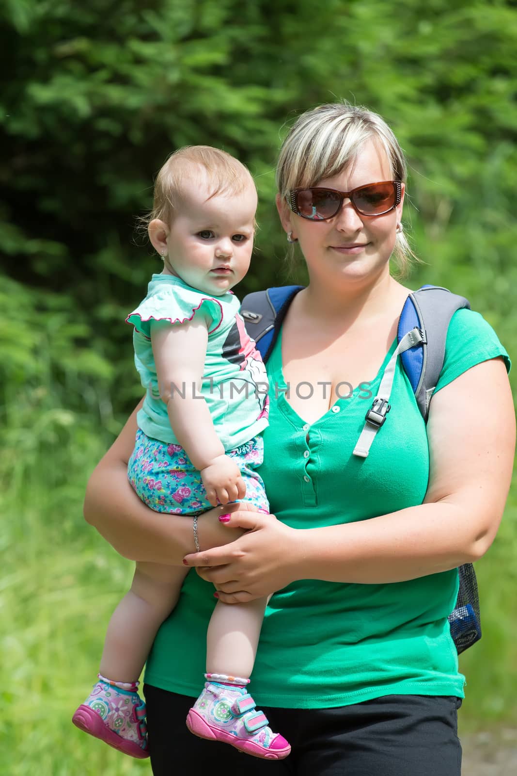 Happy baby on the mother's hands in the summer park