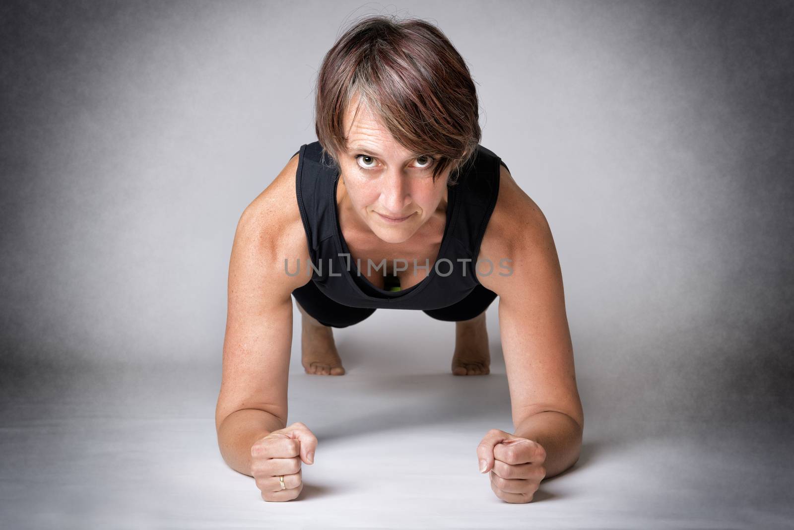 Middle aged handsome woman in forearm push-ups position