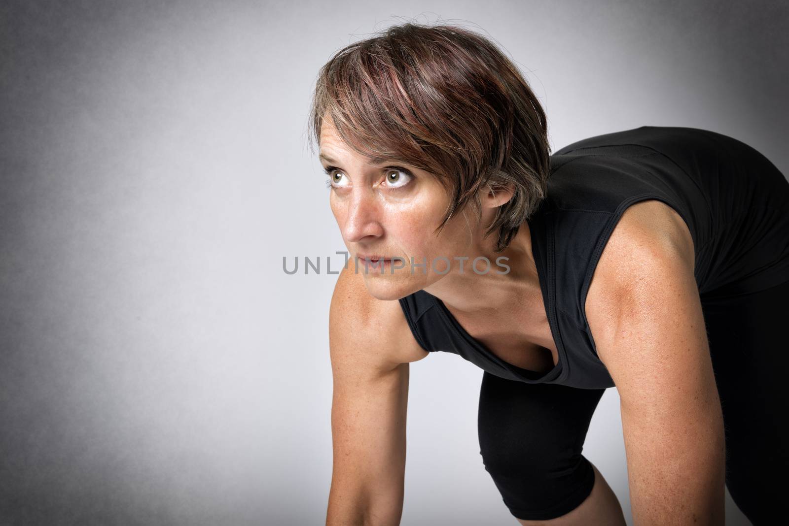 Image of running middle aged handsome woman in running start position