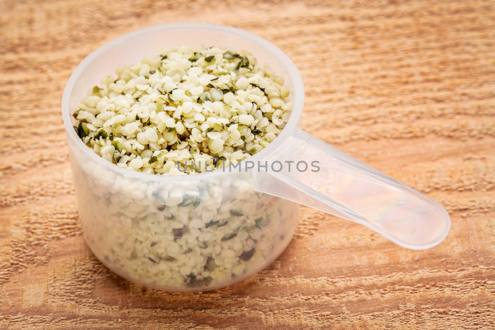 measuring scoop of hemp seed hearts against cedar wood plank