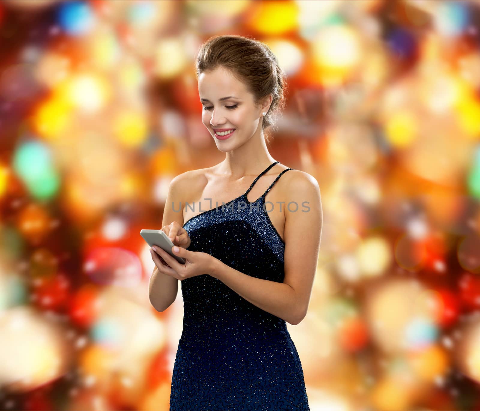 smiling woman in evening dress with smartphone by dolgachov