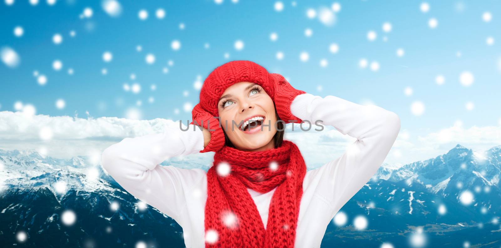 happiness, winter holidays, tourism, travel and people concept - smiling young woman in red hat and mittens over snowy mountains background