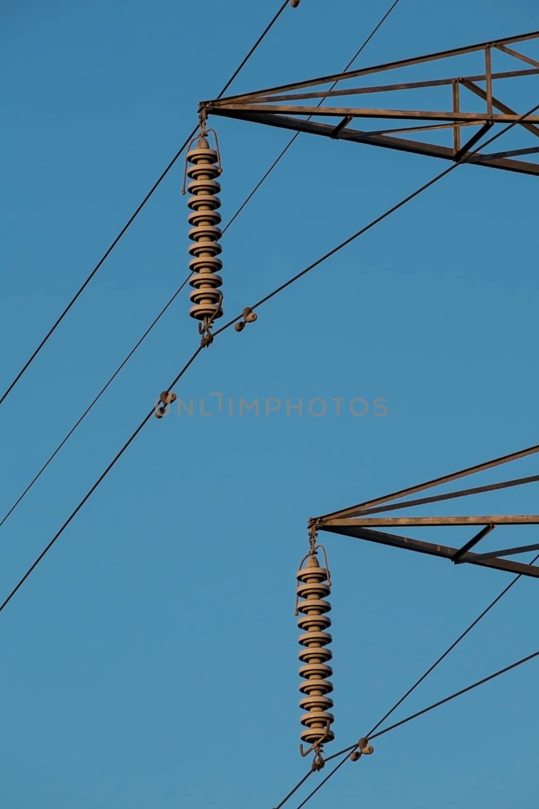 electricity pylon insulators and arms against a blue sky